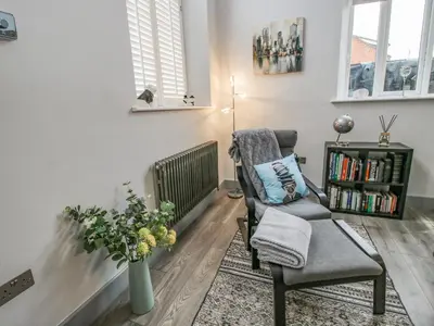 a living room with a chair and a book shelf at Wesleyan House in Oswestry