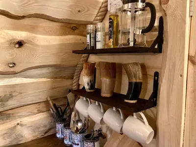 a kitchen with wooden walls and shelves with utensils at The Prancing Moose in Ystrad Meurig