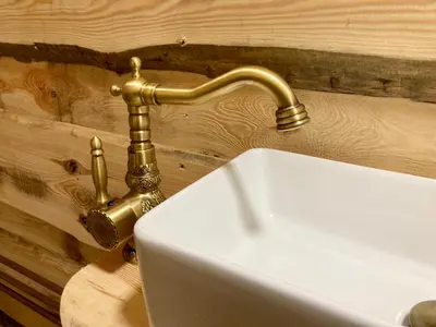 a bathroom sink with a gold faucet on a wall at The Prancing Moose in Ystrad Meurig