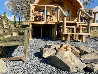 a wooden cabin with a bench and some rocks at The Prancing Moose in Ystrad Meurig
