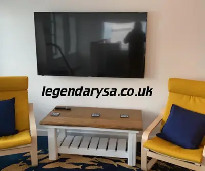 two chairs and a table and a tv on a wall at Harbour Lights Apartment New Quay in New Quay