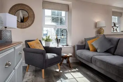 a living room with a couch and a chair at Seagrass Cottage - Aberdovey in Aberdyfi
