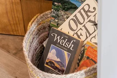 a basket filled with books on a table at Seagrass Cottage - Aberdovey in Aberdyfi