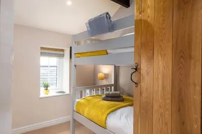 a bedroom with a bunk bed and a window at Seagrass Cottage - Aberdovey in Aberdyfi
