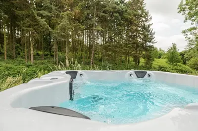 a hot tub with blue water in a field at Riverside Cabins in Shrewsbury