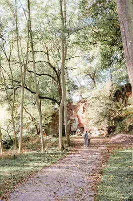 two people walking down a dirt road with trees at Riverside Cabins in Shrewsbury