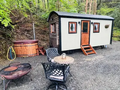a small shed with a table and a grill at Romantic Shepherds Hut with Hot Tub in The Heart of Snowdonia in Dolgellau