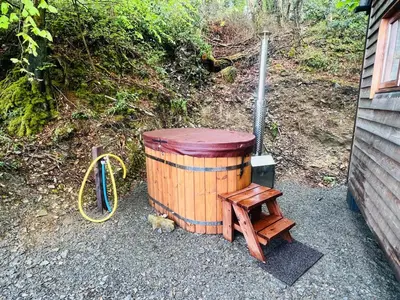 a wooden barrel sitting next to a wooden stool at Romantic Shepherds Hut with Hot Tub in The Heart of Snowdonia in Dolgellau