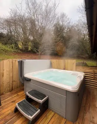 a hot tub sitting on a wooden deck with at Solid Log Cabin With Private Hot Tub - Oak in Aymestrey