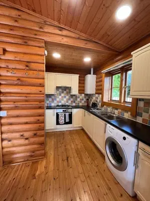 a kitchen with a washer and dryer in a cabin at Solid Log Cabin With Private Hot Tub - Oak in Aymestrey