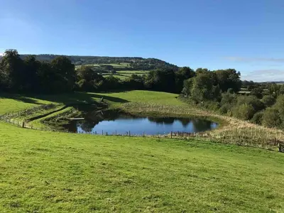 a green field with a pond in the middle at 3 Bed in Talybont-on-Usk oc-wal376 in Talybont