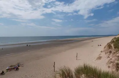 a beach with people on the sand and the ocean at 2 Bed in Barmouth oc-wah699 in Talybont