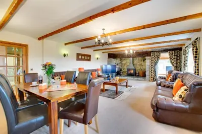 a living room with a wooden table and leather chairs at 5 Bed in Aberystwyth oc-wan443 in Llanychaiarn