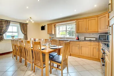 a kitchen with a wooden table and wooden chairs at 5 Bed in Aberystwyth oc-wan443 in Llanychaiarn