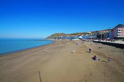 a group of people on a beach near the water at 1 Bed in Aberystwyth oc-bow182 in Rhostie