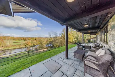 a patio with chairs and a table and a view of a river at 4 Bed in Builth Wells oc-bow197 in Builth Wells