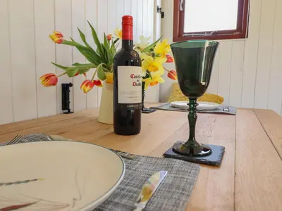 a bottle of wine and a glass on a table at Balwen Shepherd's Hut in Montgomery