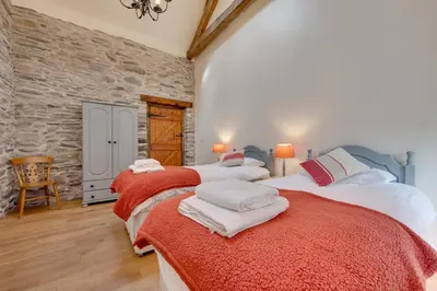 two beds in a bedroom with a stone wall at 4 Bed in Llanarmon Dyffryn Ceiriog oc-bow152 in Llanarmon Dyffryn-Ceiriog