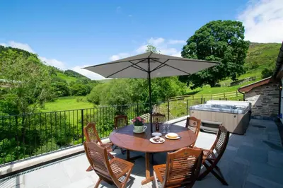 a table and chairs with an umbrella on a patio at 4 Bed in Llanarmon Dyffryn Ceiriog oc-bow152 in Llanarmon Dyffryn-Ceiriog